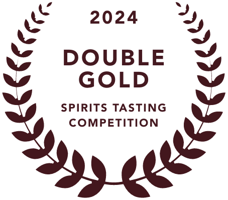 A circular badge with a maroon laurel wreath border. The text reads '2024 Double Gold Spirits Tasting Competition' an award presented to mala mía mezcal, positioning them among the best mezcal 2024.