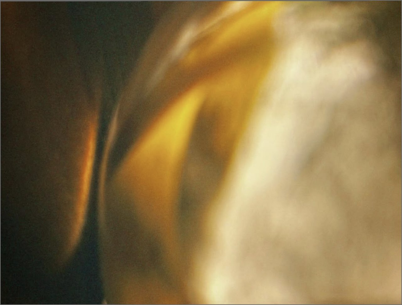 Close-up of a smooth, shiny, golden surface with a blurred background.