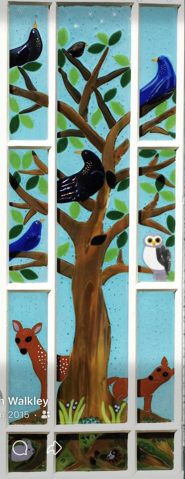 Colorful painting of a tree with various animals including birds, an owl, a fawn, a fox, a raccoon, and a snake, set against a blue sky background.