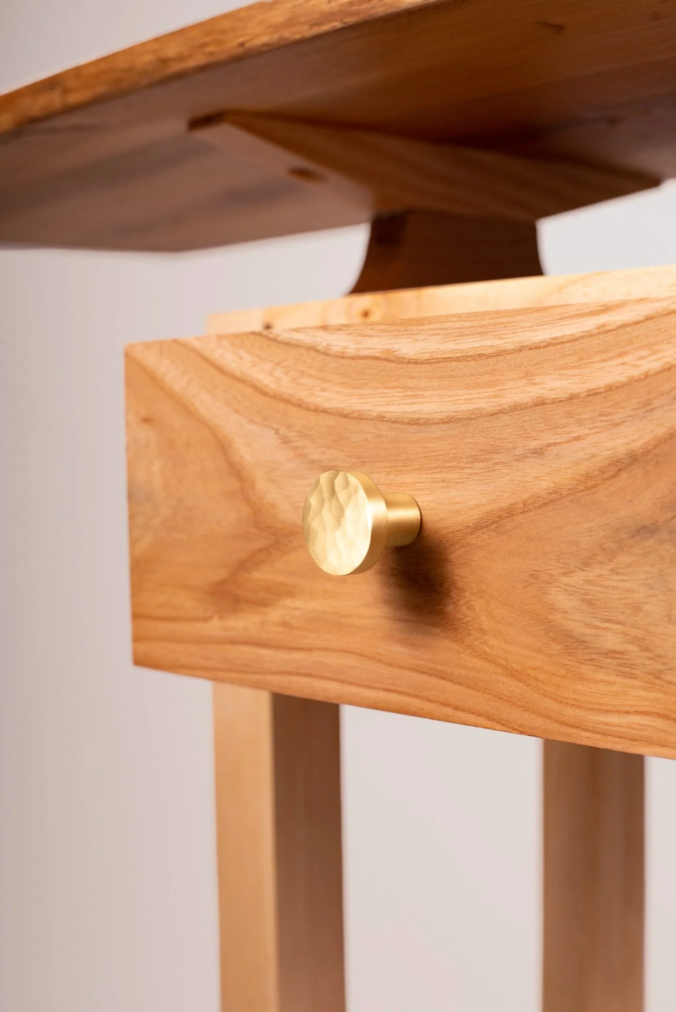 Close-up of a wooden side table with a brass knob.
