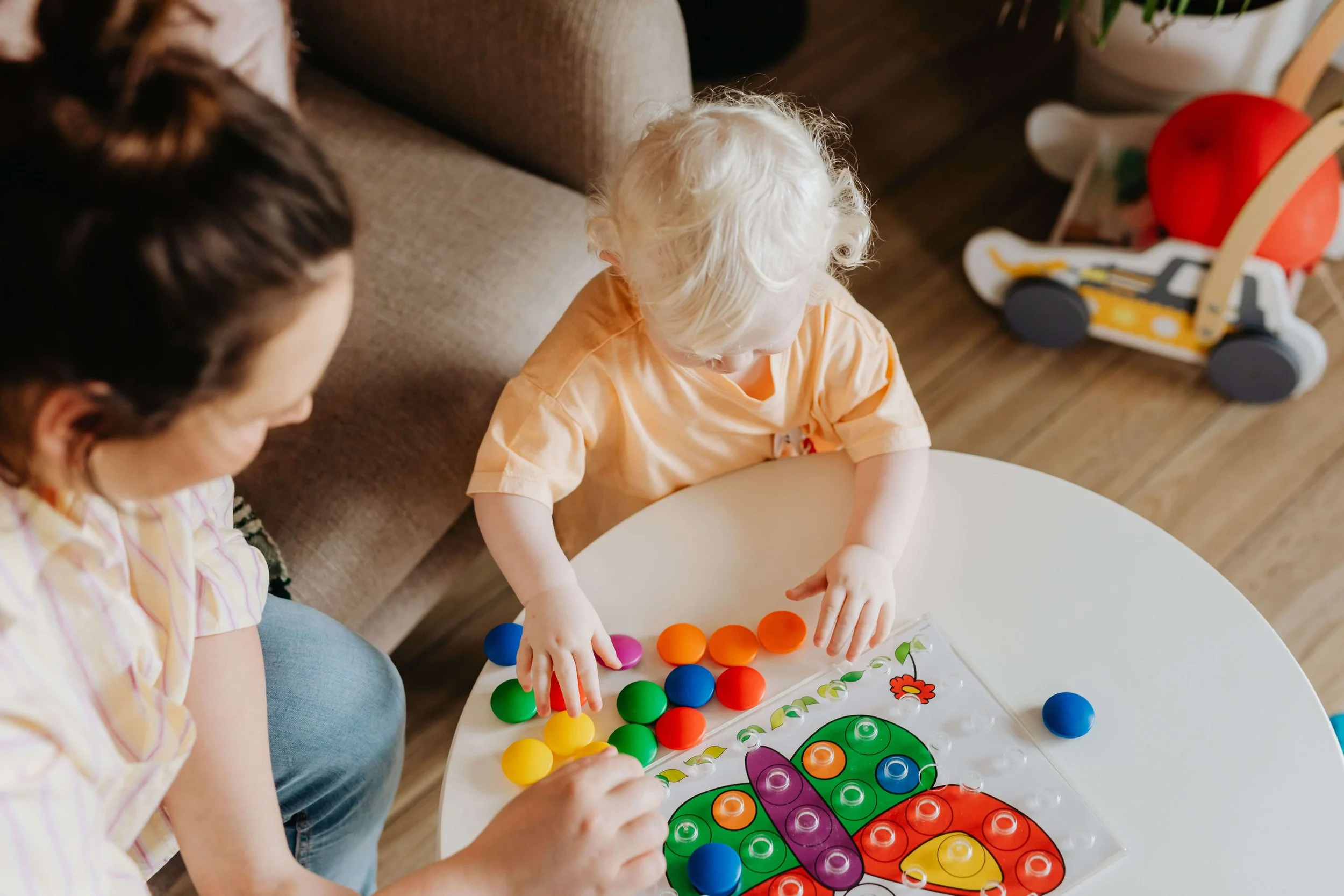 An adult and young child playing with colorful fine motor toys to play and make a design together during a child-led speech therapy session in Olympia, WA.