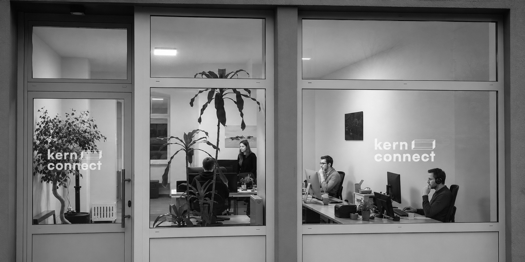 Büro mit vier Personen, die an Computern arbeiten, zwei auf der rechten Seite mit Kopfhörern, und zwei auf der linken Seite. Fenster mit der Aufschrift "kern connect" jeweils auf der Tür und Wand.