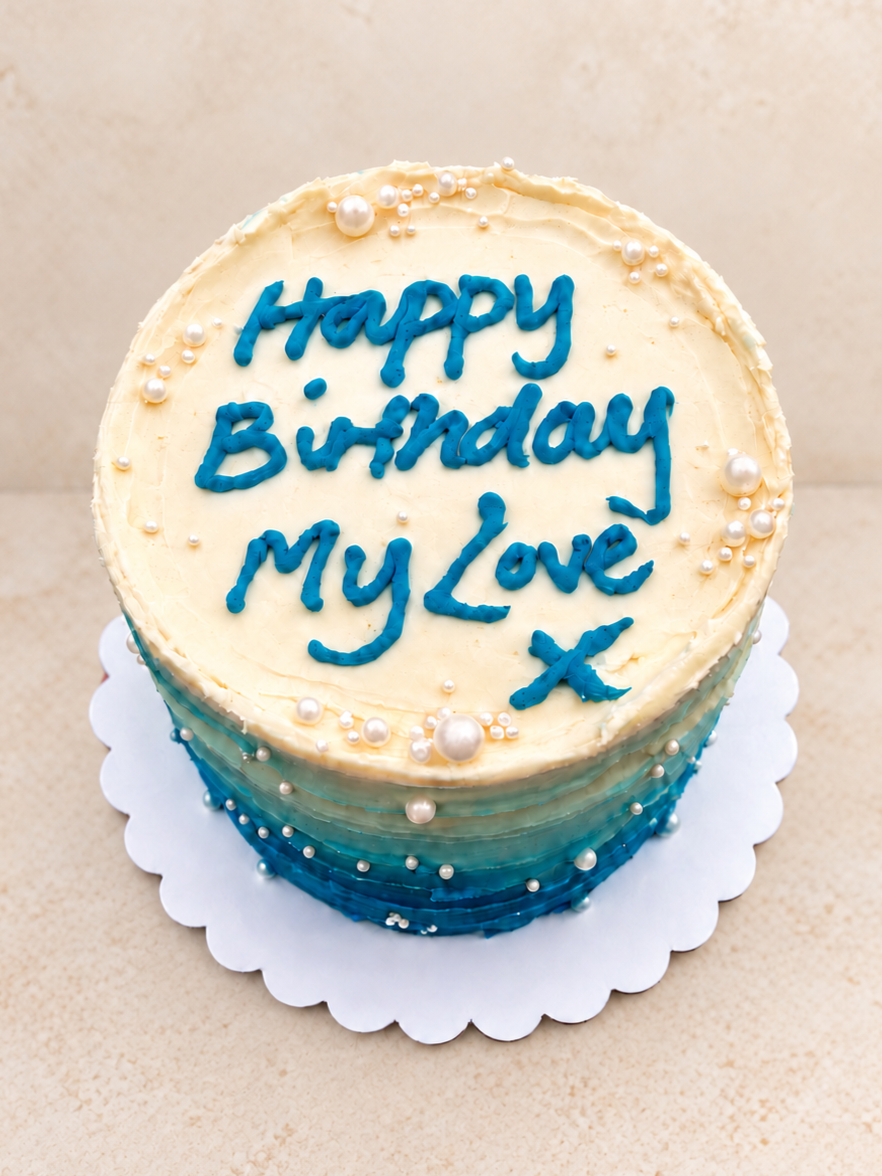 Bento cake with white to blue ombré icing, decorated with silver and pearl-like edible beads, and blue personalised message