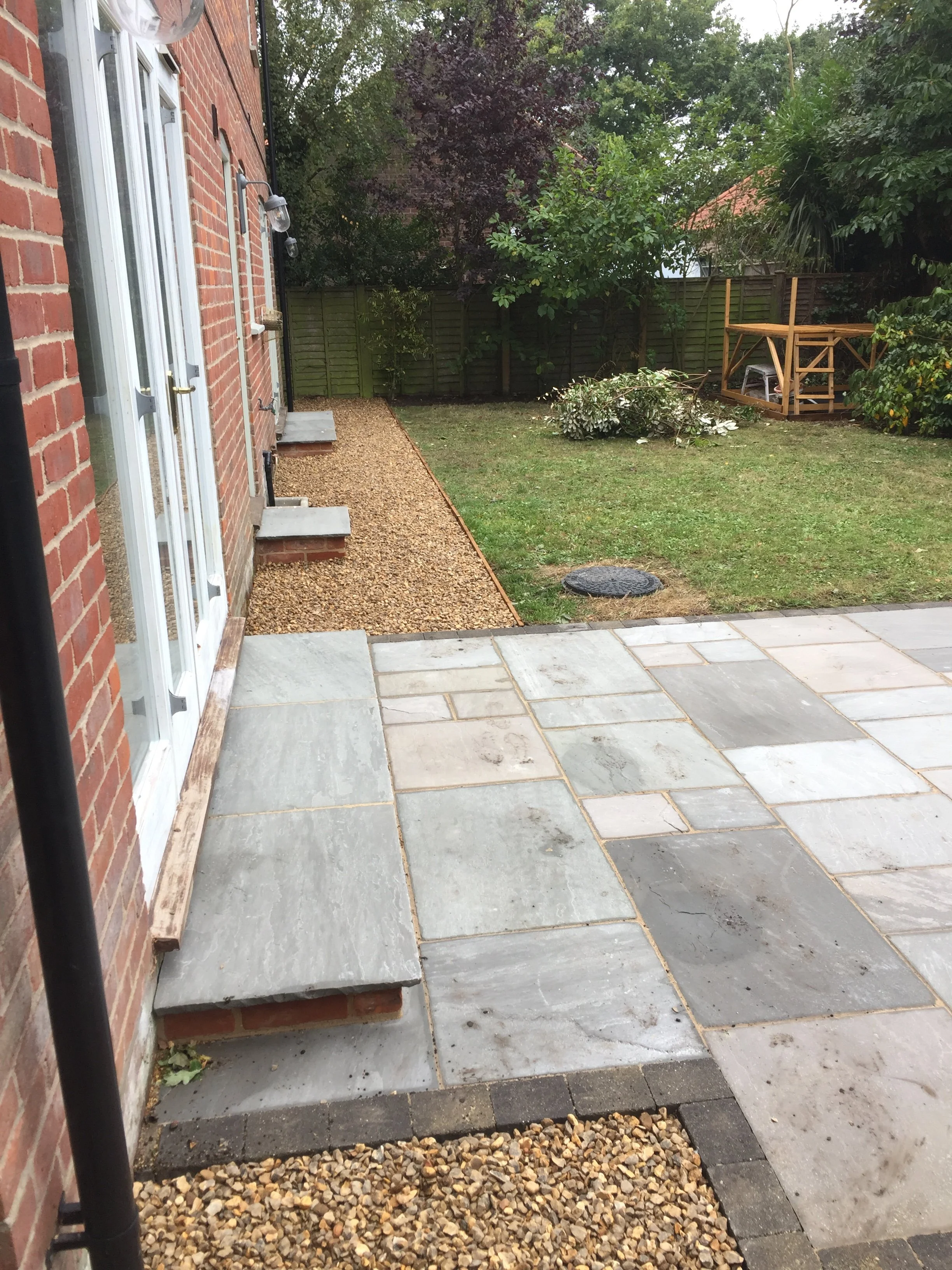 Backyard with a market, patio, greenery, and a small raised garden bed near a brick house.