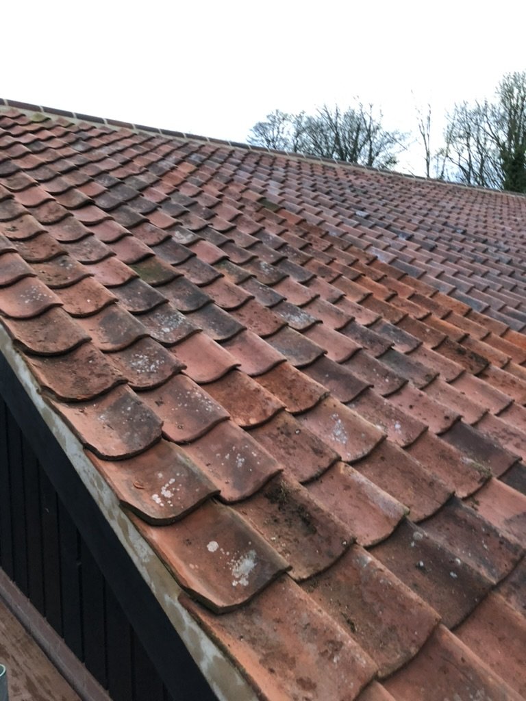 Close-up of an old roofing roof with red clay tiles, some covered in dirt and moss.