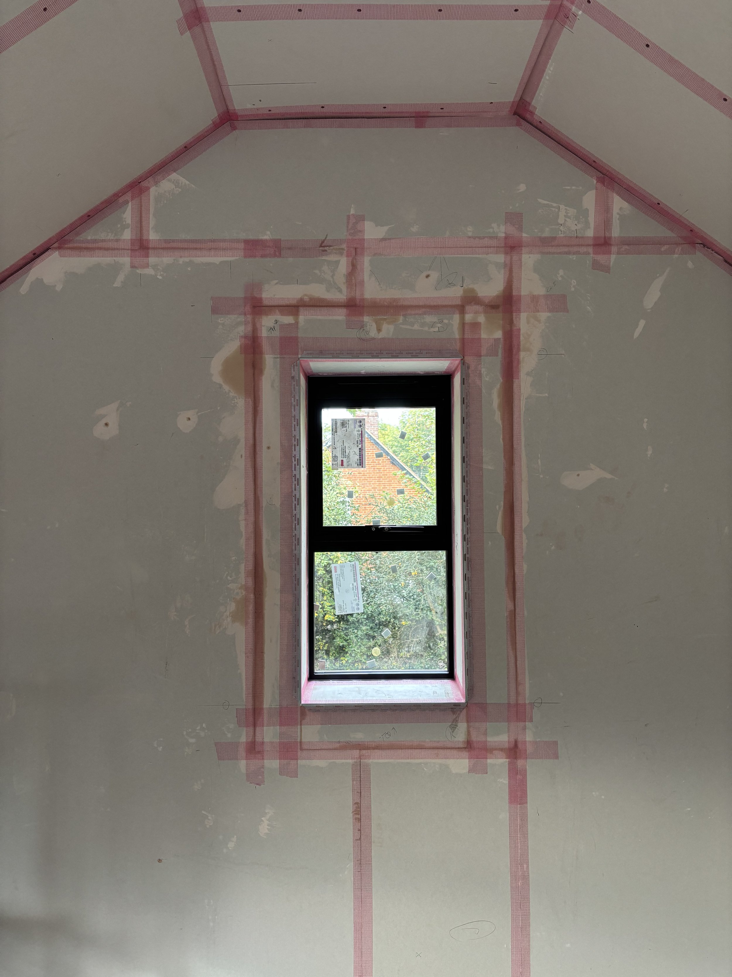 Ceiling with drywall and tape, with a rectangular window near the bottom and red painter's tape outlining the framing area.