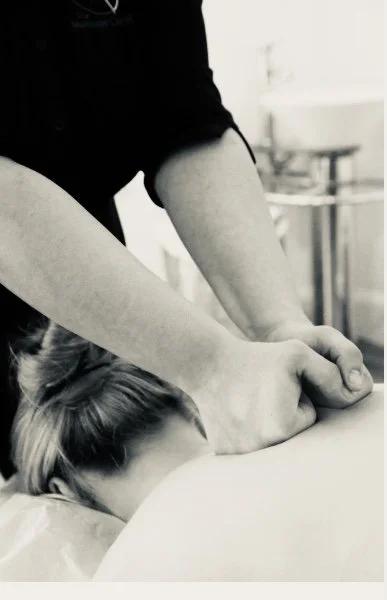 A person receiving a massage or physical therapy on their neck or shoulder, with part of their head resting on a surface.