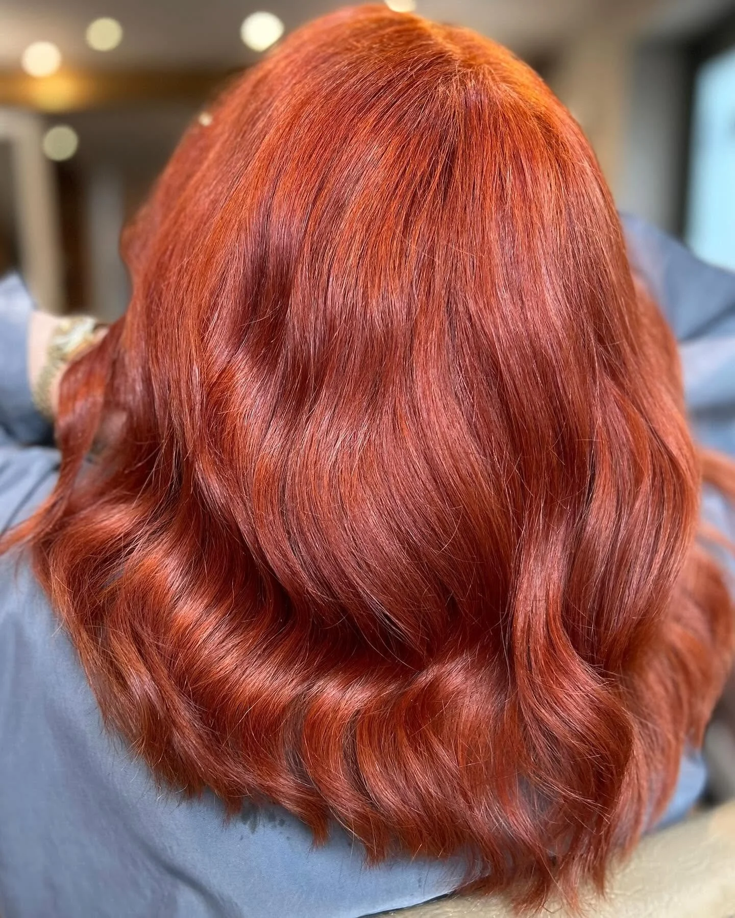Close-up of vibrant, shiny red hair with loose curls.