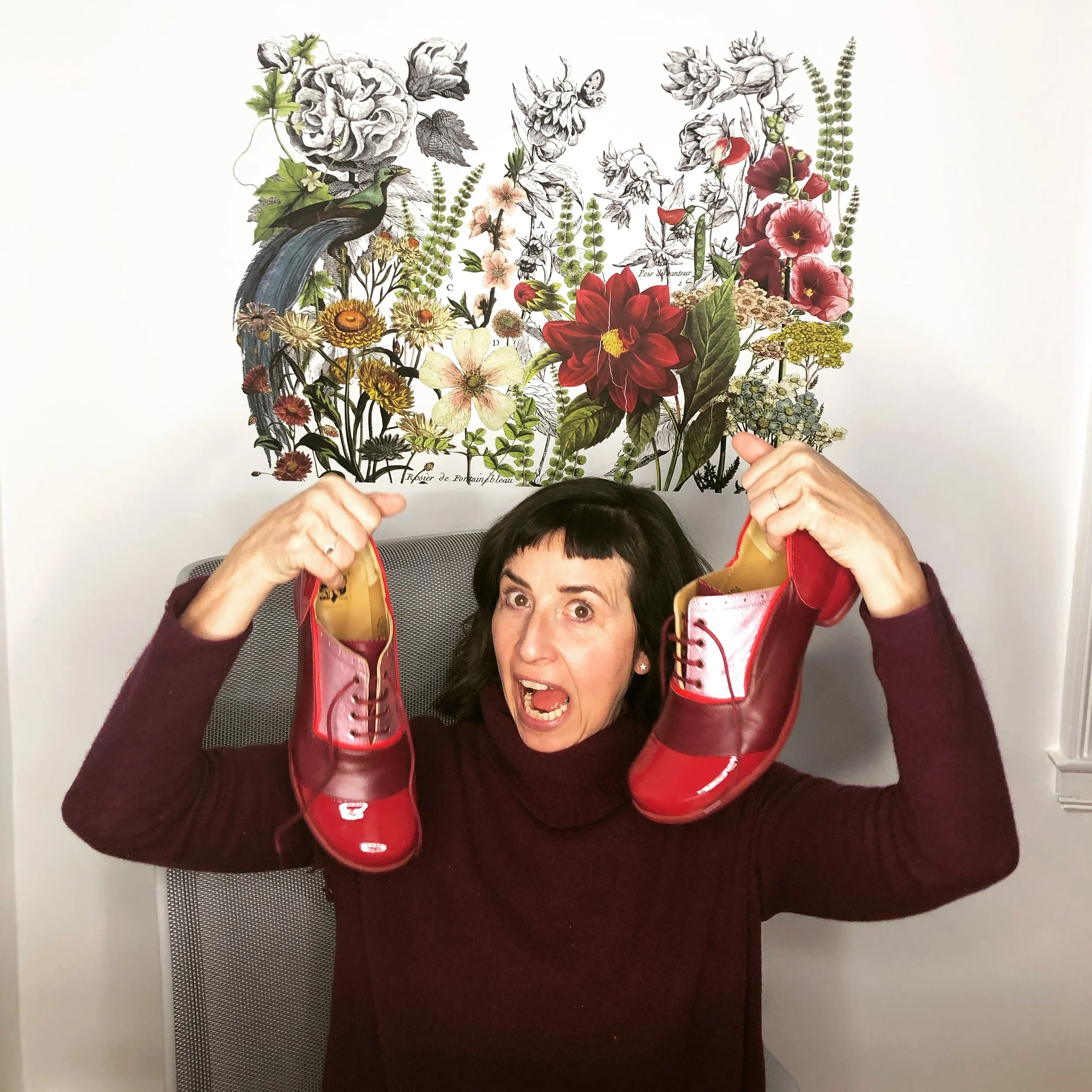 Sea Conlin holding a white and red shoe over their head, with a wall in the background