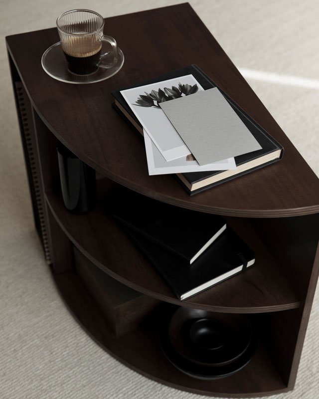 A dark table with a coffee cup, papers, and notebooks atop it.