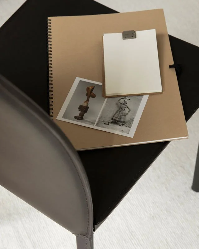 Pages and notebooks on a black chair.