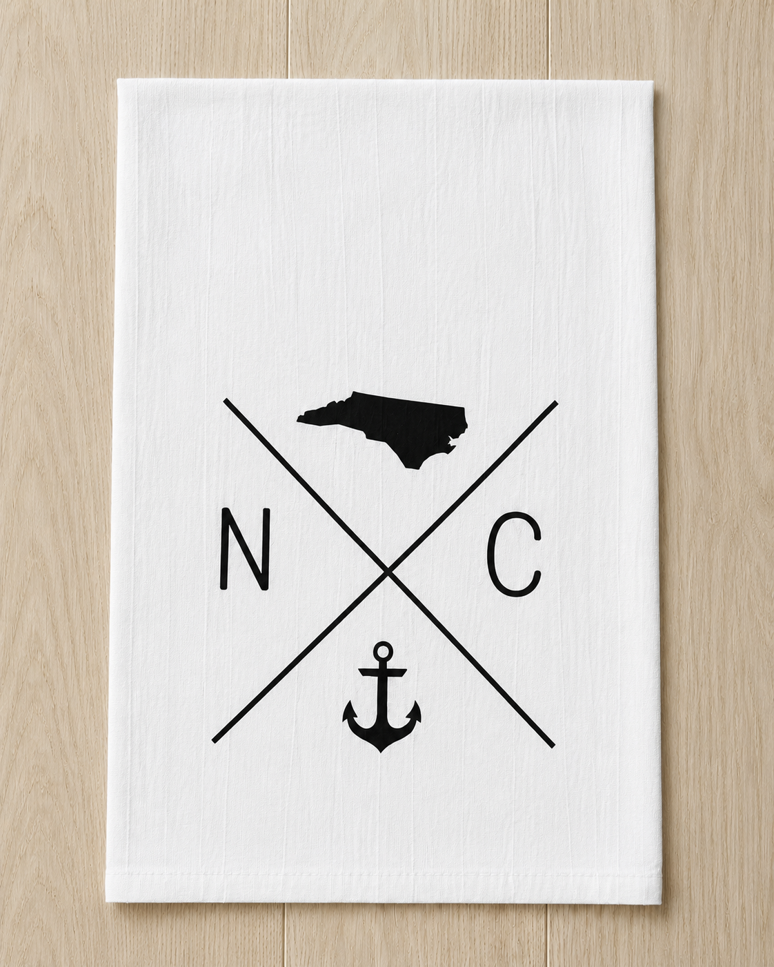 White fabric with black graphic design of the state of North Carolina, a nautical anchor, and crossed lines with the letters N and C.