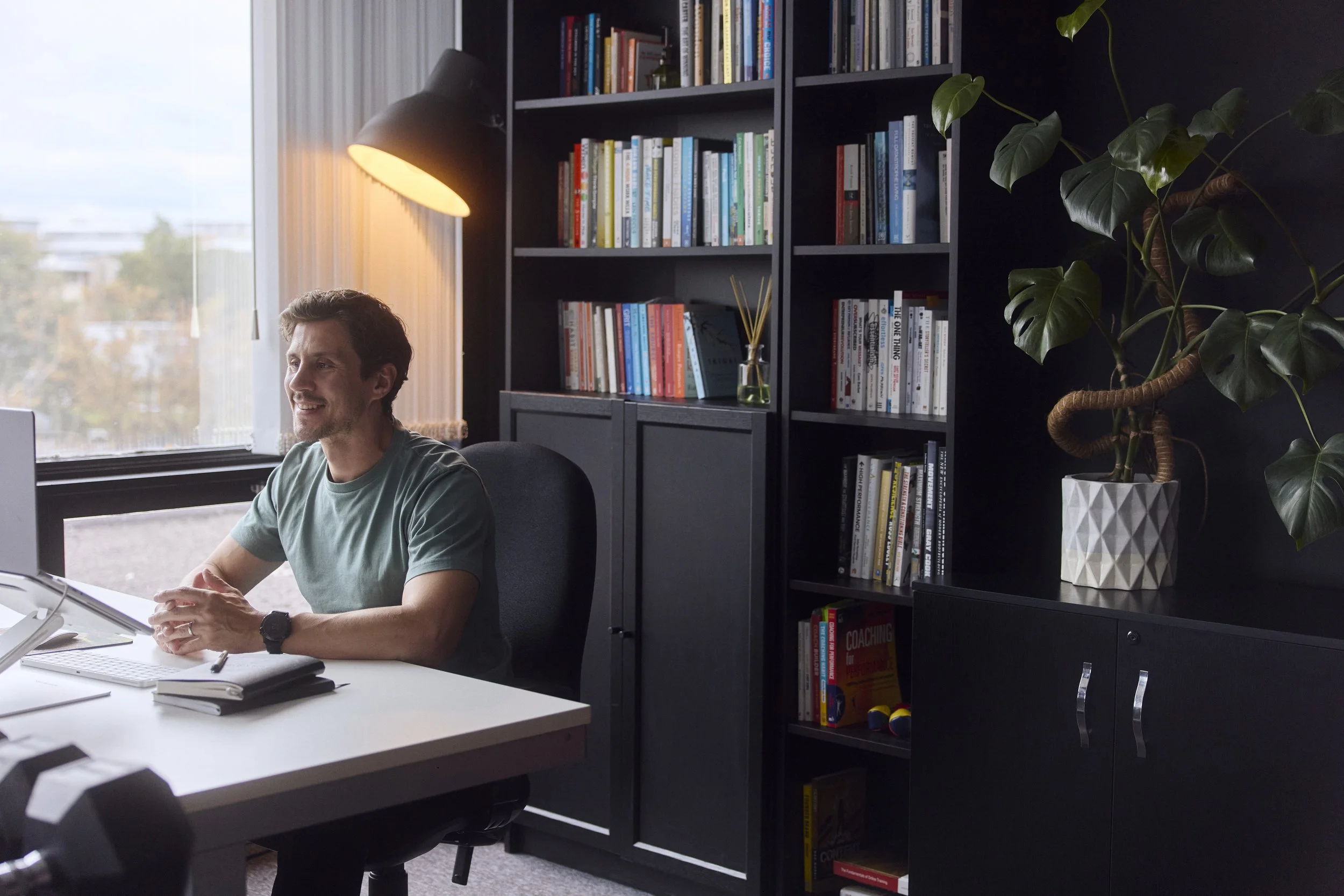 Robbie Thompson working at a desk, smiling, engaging with computer screen.