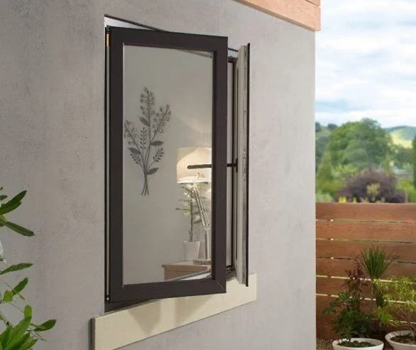 Open window with a black frame on a gray wall, revealing a view of a backyard with green trees and a wooden fence.