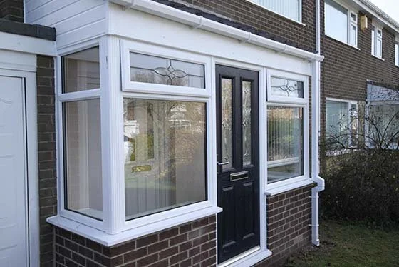 Front porch with black door and large windows, brick exterior house