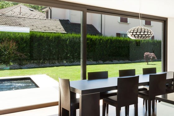 Modern dining room with a large window overlooking a green backyard