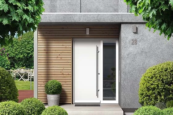 Modern house entrance with white door, wooden accent wall, potted plant, and well-manicured bushes.