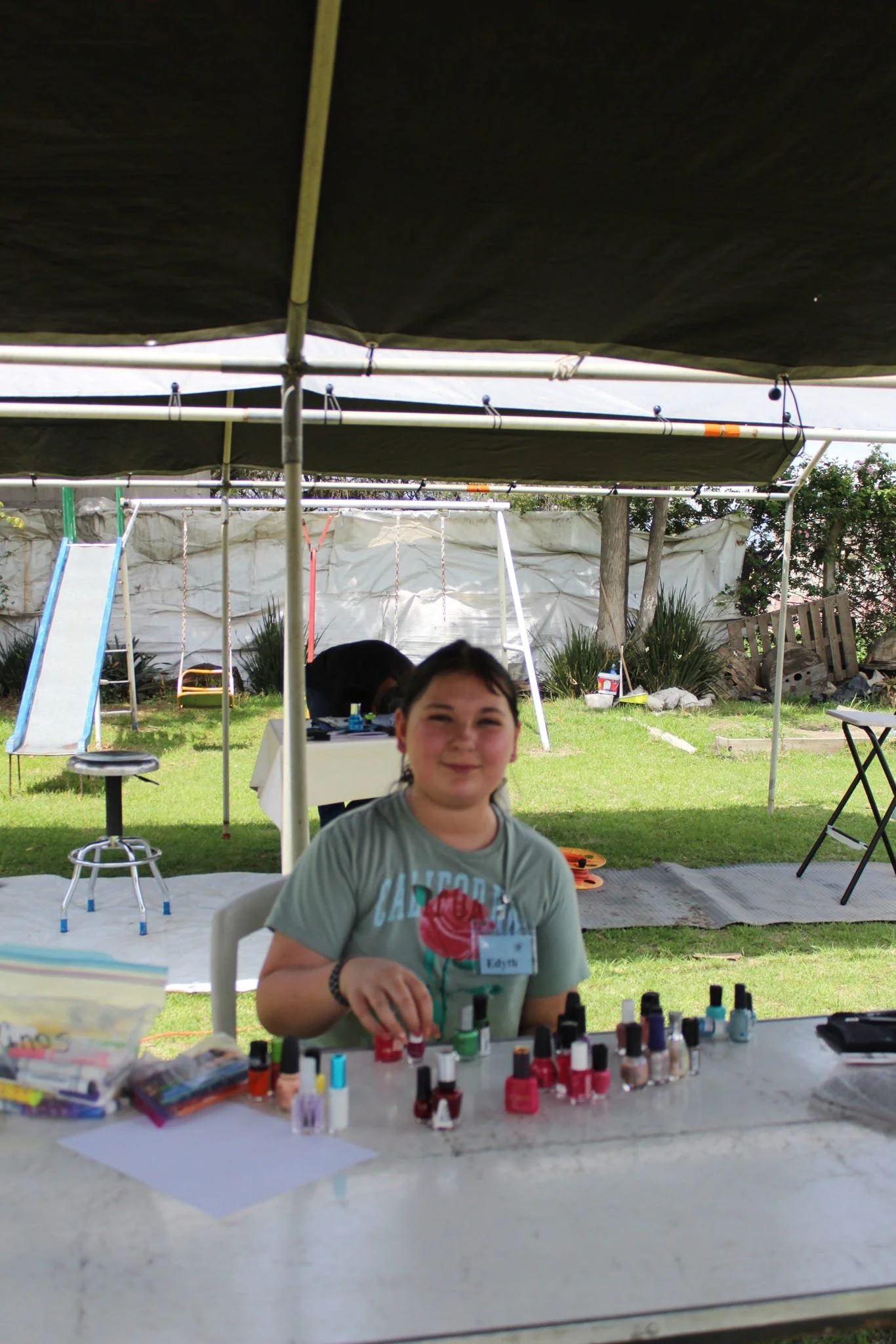 Young volunteer assisting with nail painting and activities during a children's outreach event.
