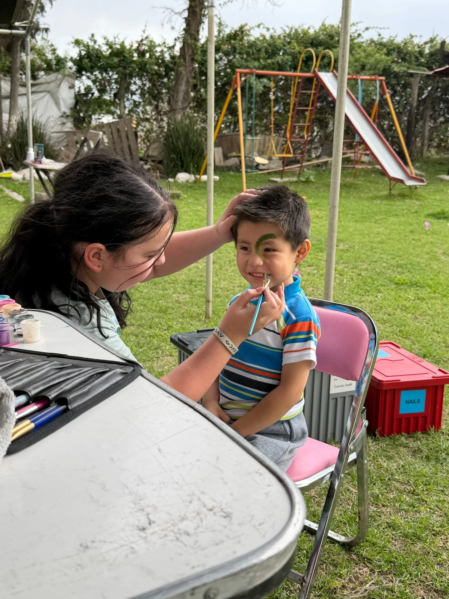 Volunteer painting a smiling child's face during an OSI children's ministry event.