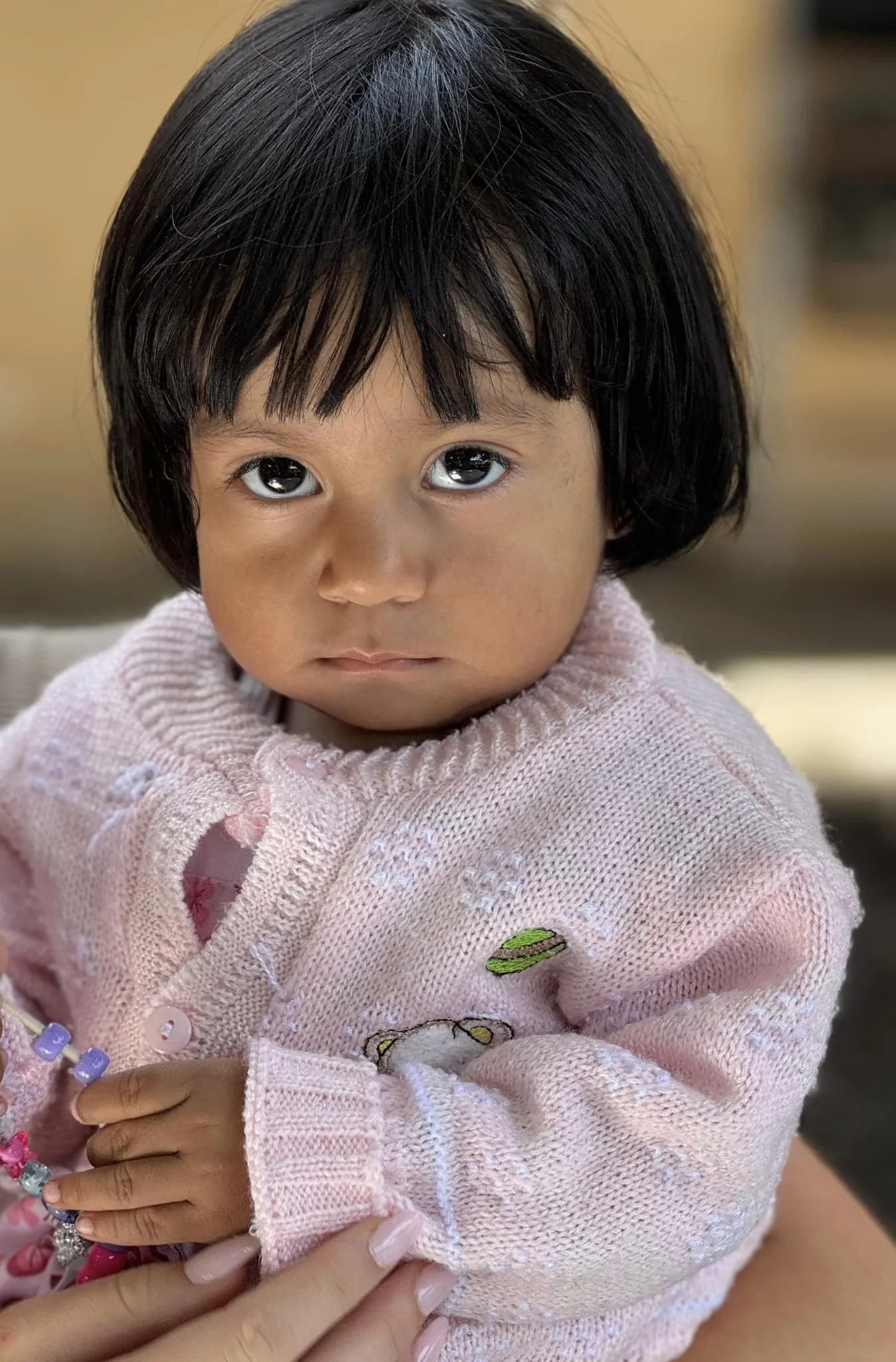 A Toddler holding colorful beads during an Operation Serve International children's outreach.