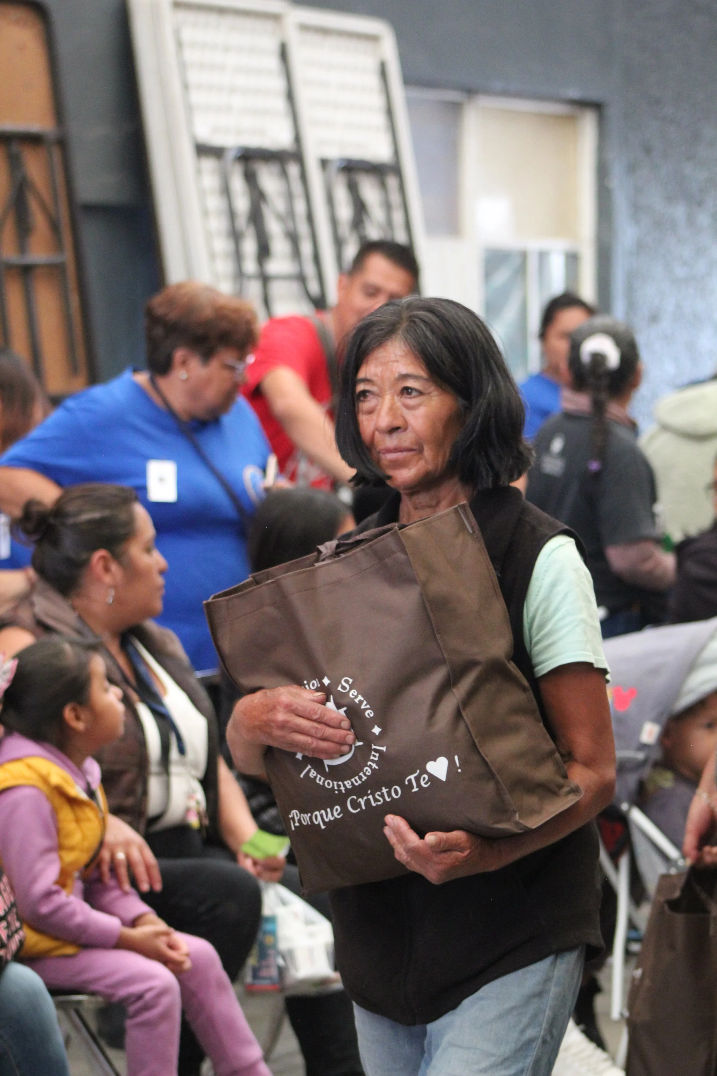 Woman walking with a large bag of donations she just received from Operation Serve International's outreach