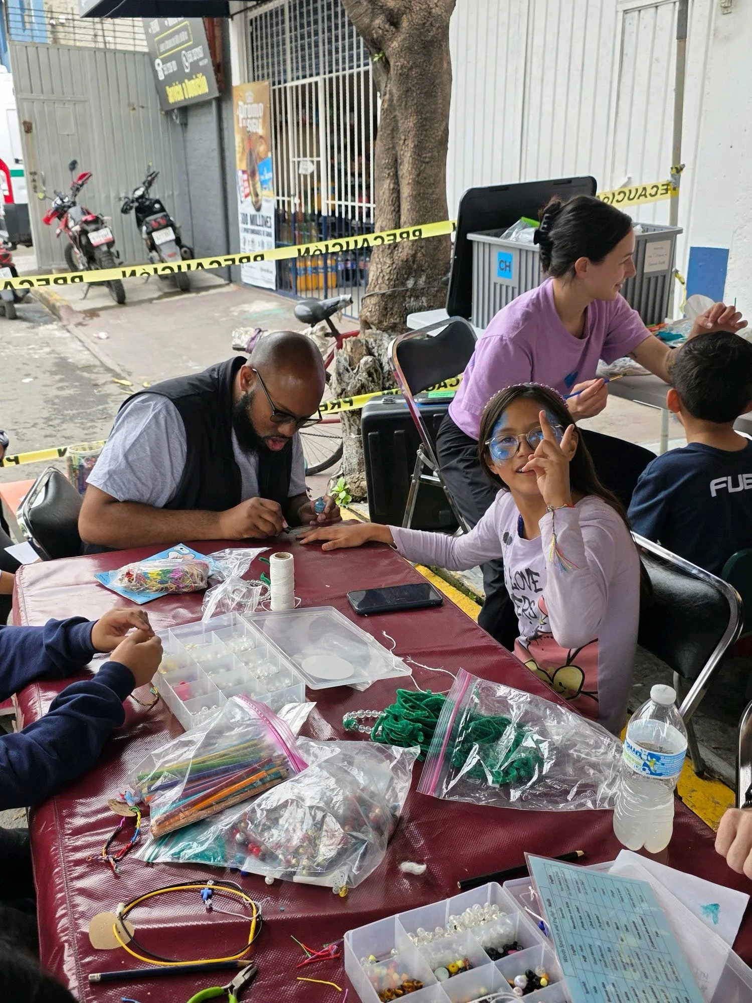 Volunteer paints a young girl's fingernails as she smiles and poses for the picture