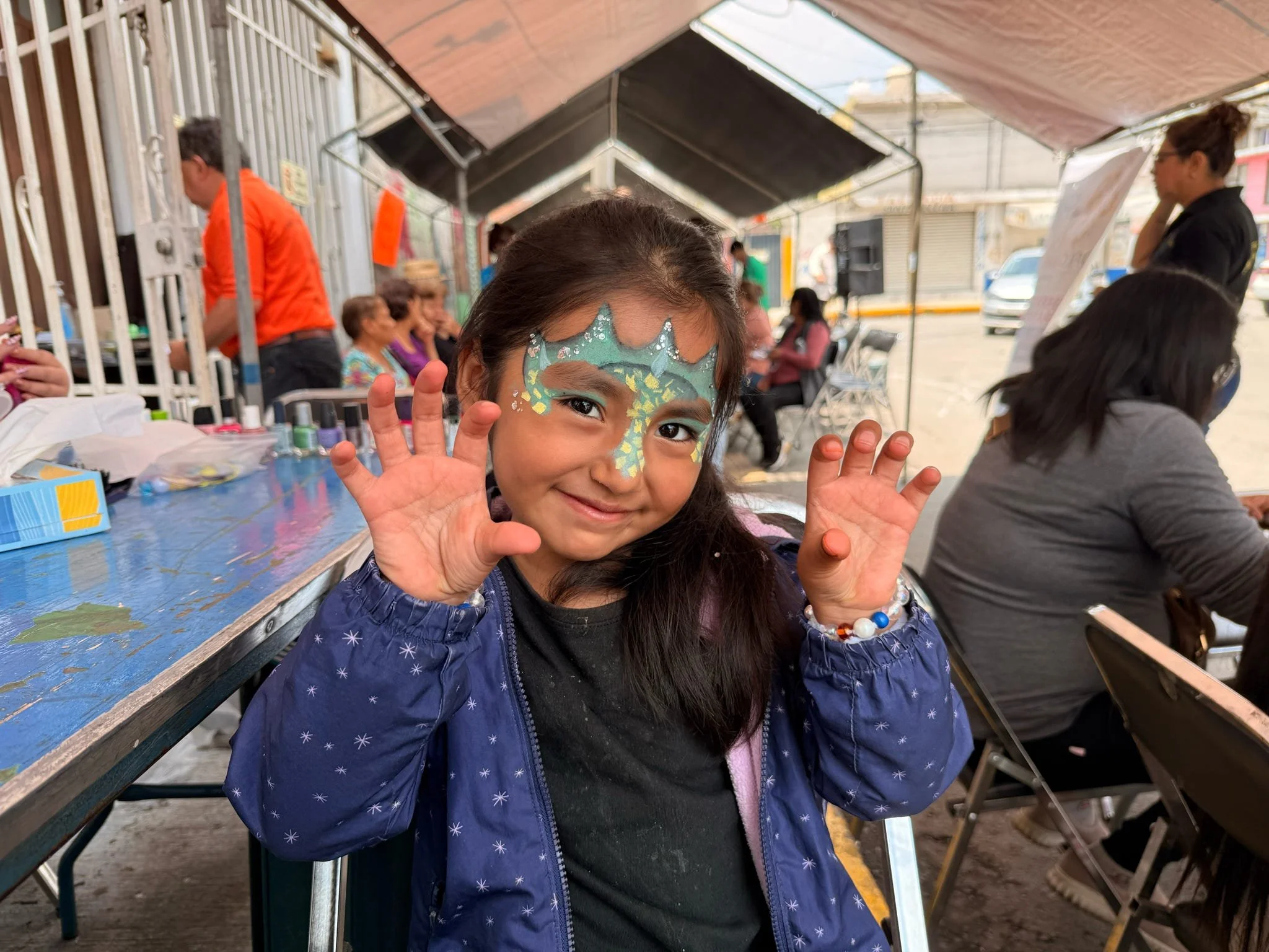 Young girl showing off colorful face paint during an Operation Serve International children's outreach.