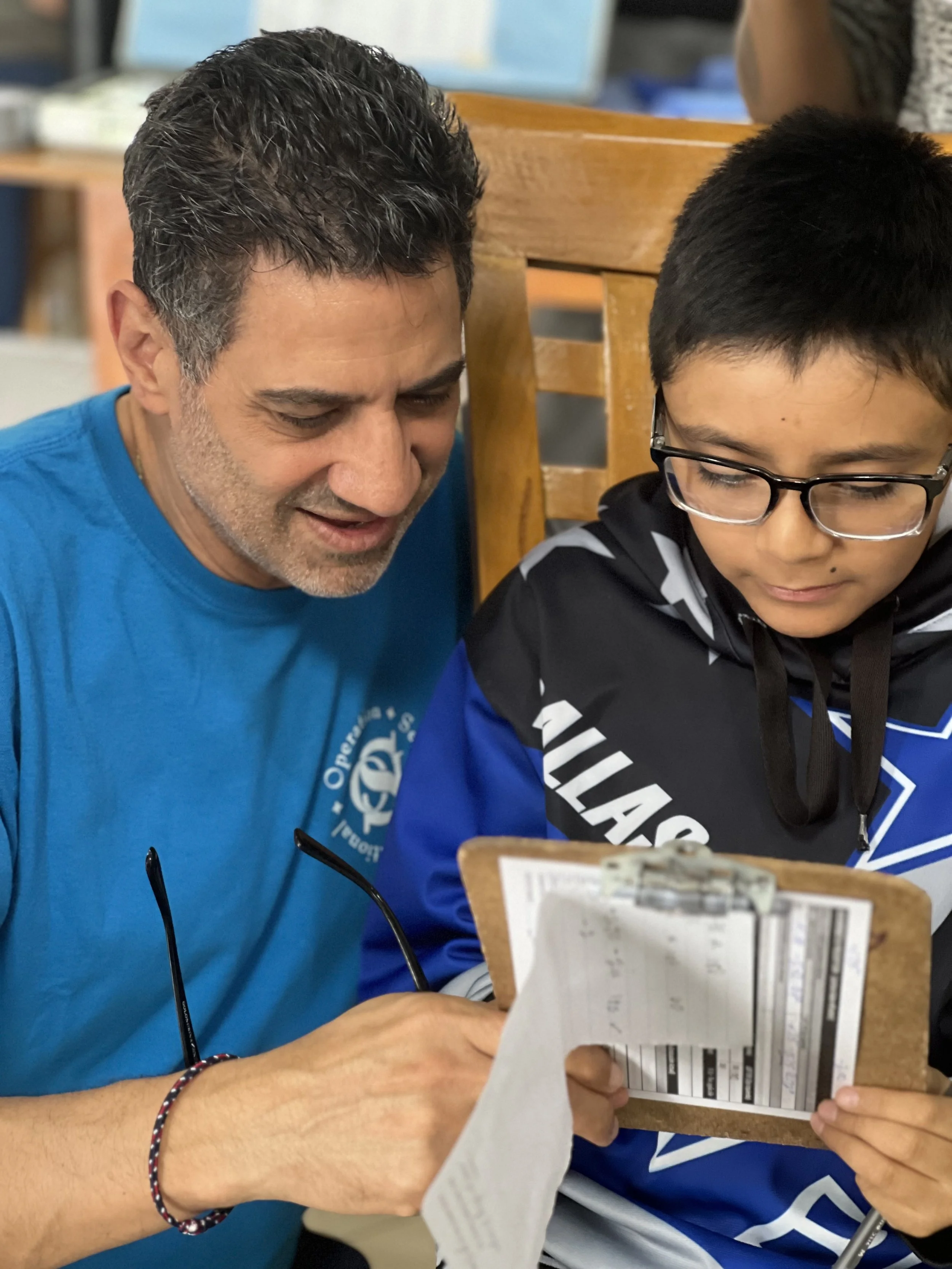 OSI Executive Director helping a child with paperwork during a community medical outreach.