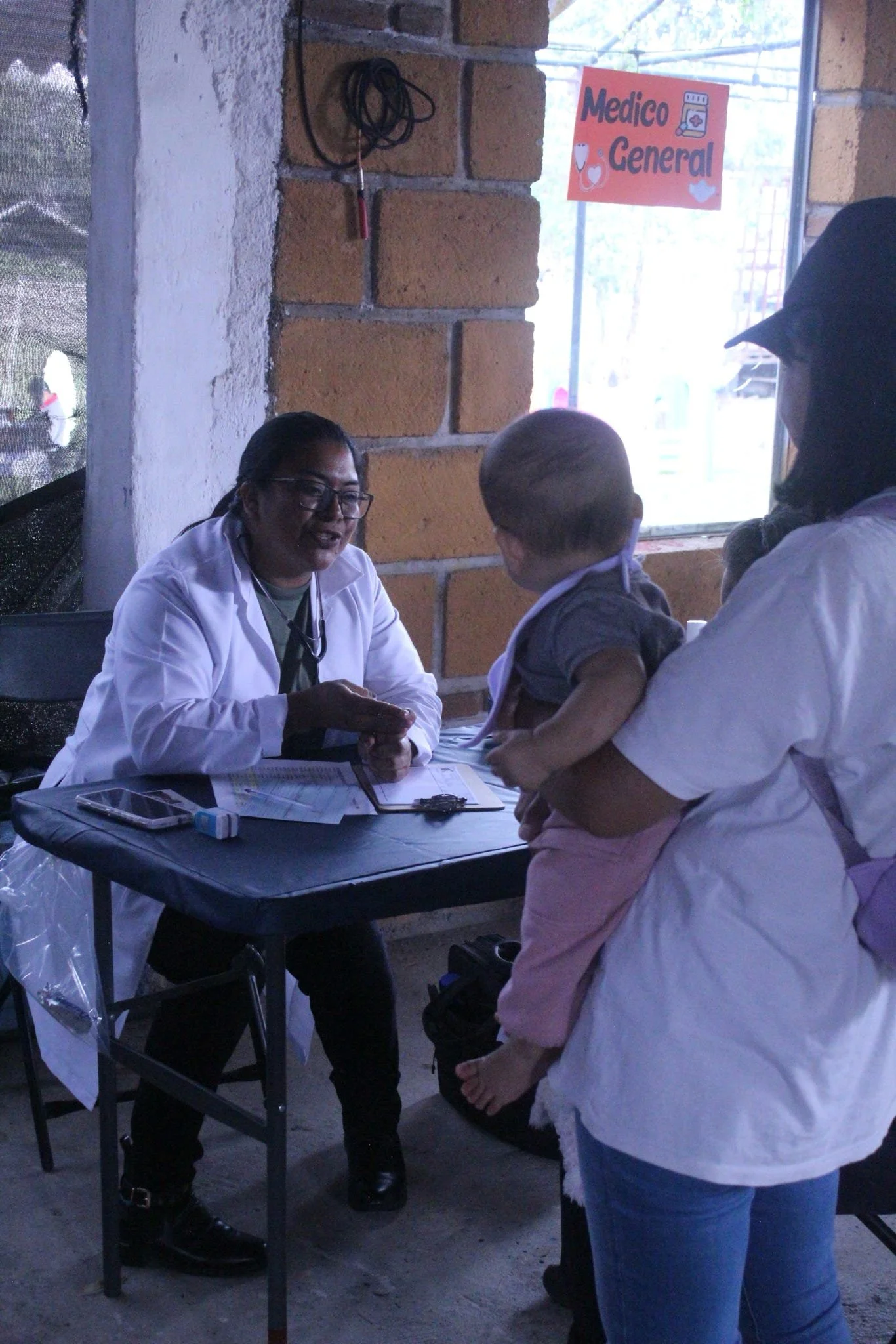 Medical professional consulting with a mother and child during an Operation Serve International medical clinic.