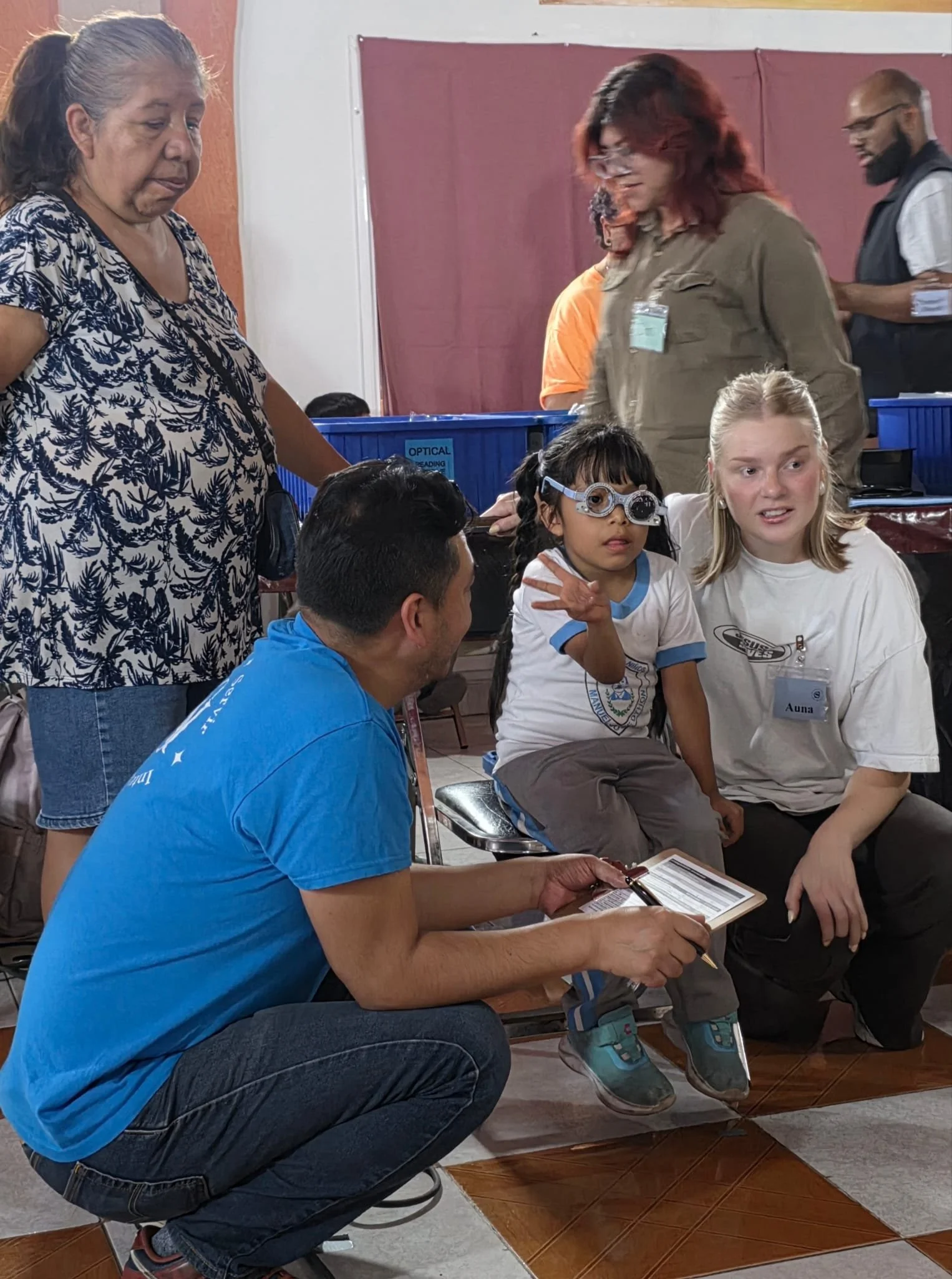 Volunteers assisting a young girl during a vision screening at an Operation Serve International medical clinic.