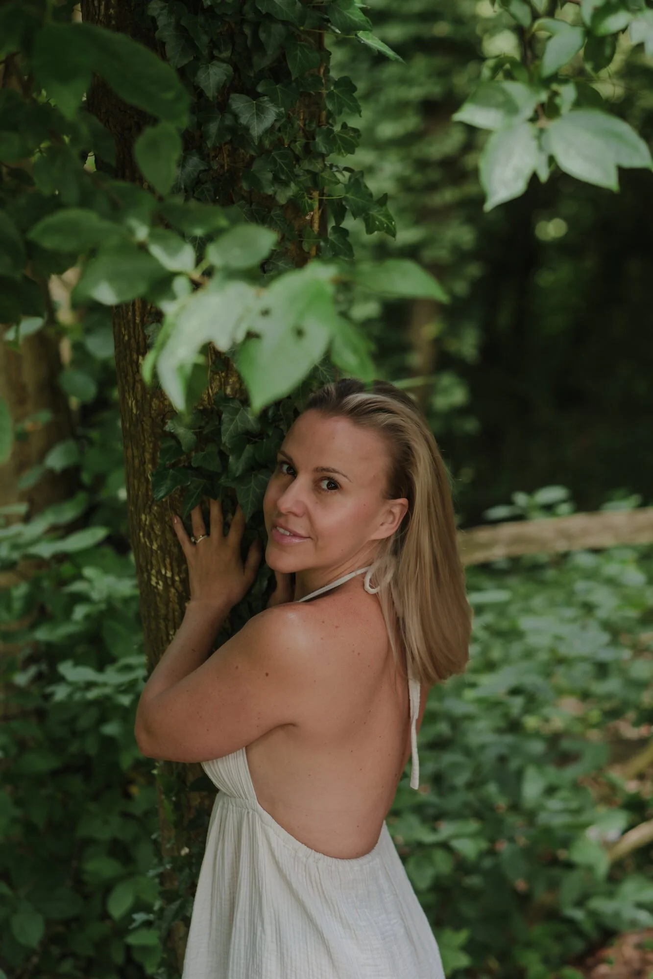 Jessica smiling among the trees in the gardens at Bury Court Barn