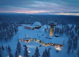 Aerial view of Arctic Resort Kakslauttanen buildings and glass igloos in a snowy forest at dusk, aurora tour pickup point