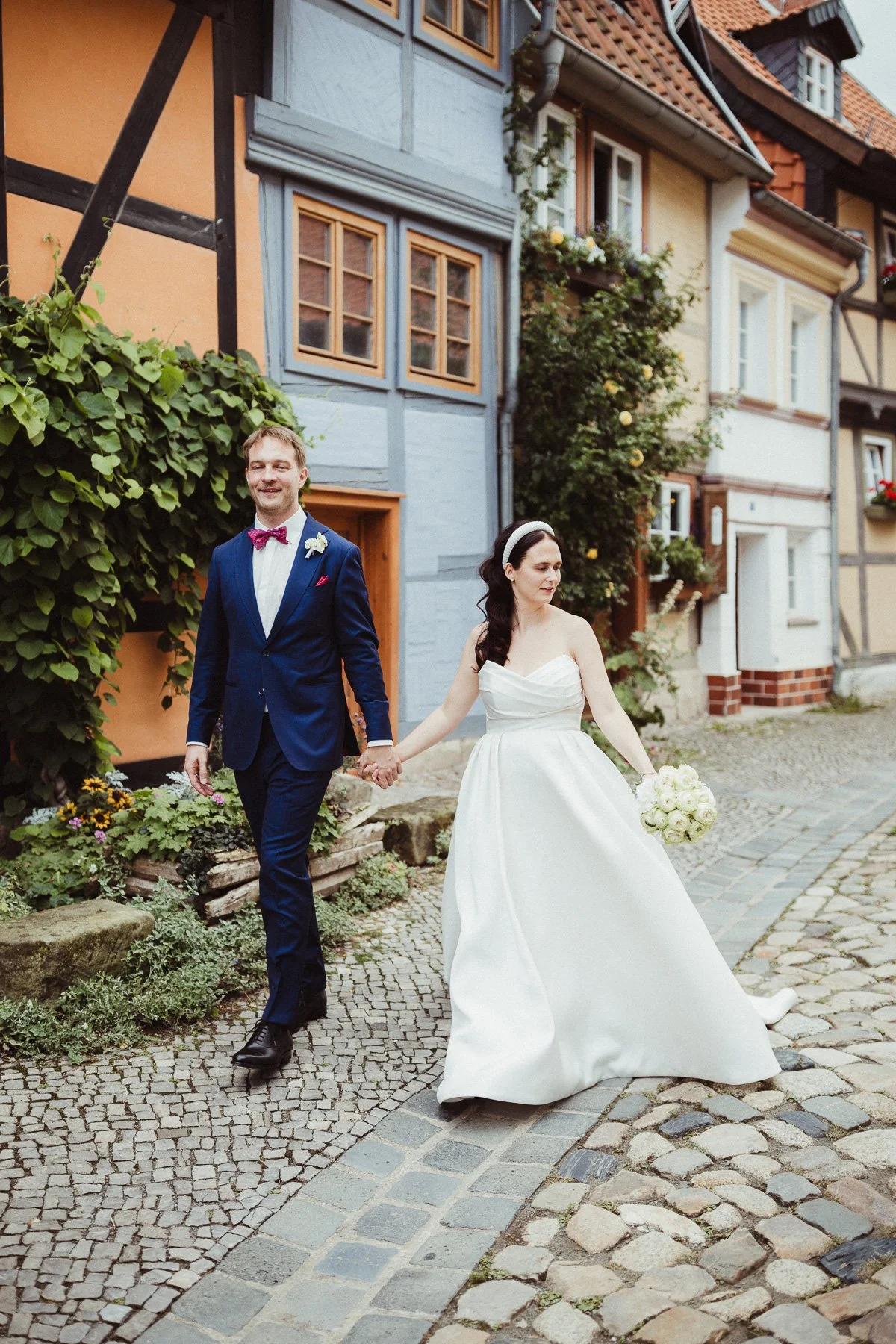 Brautpaar schlendert durch kleine Gasse mit Kopfsteinpflaster