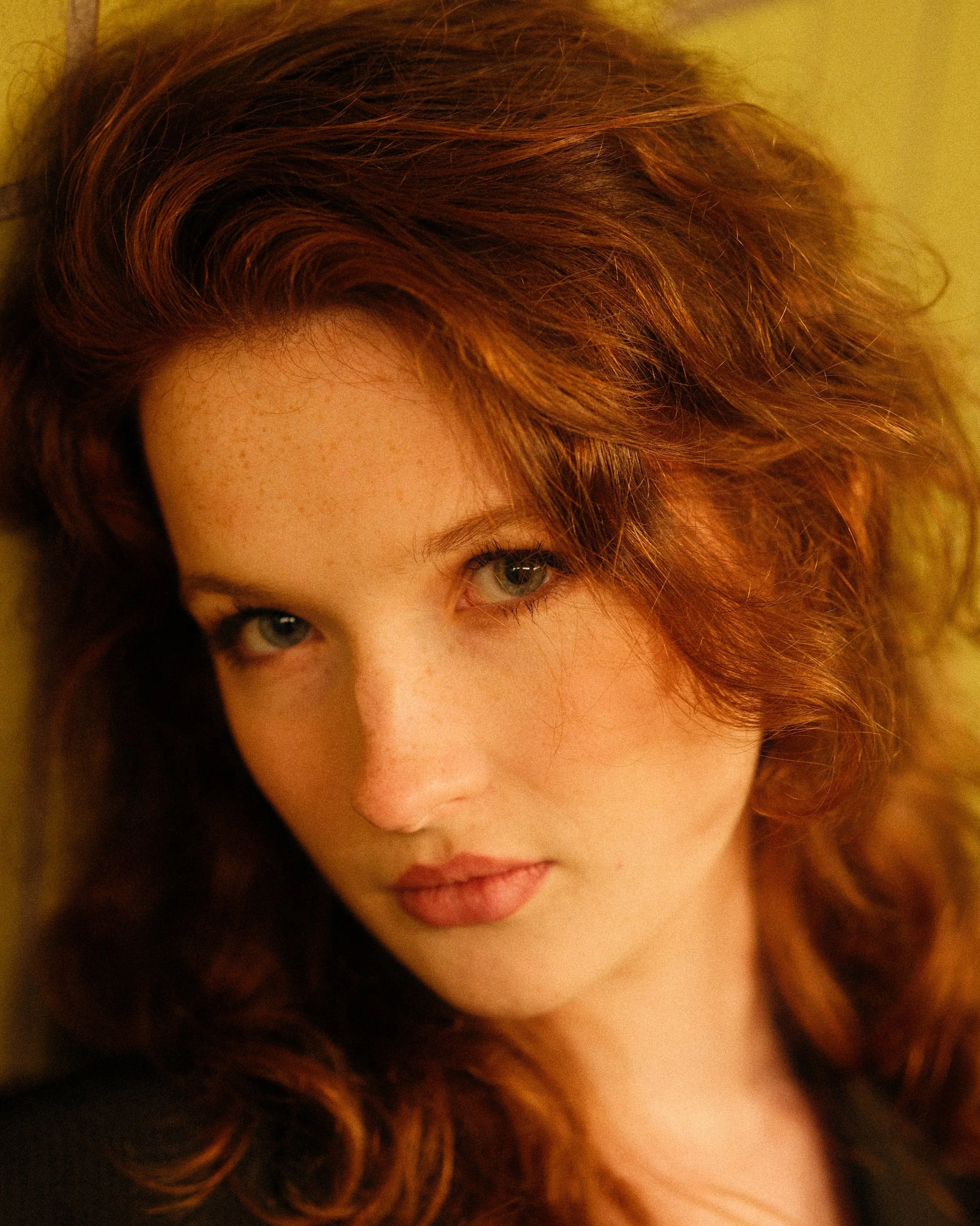Nahaufnahme eines Teils des Gesichts einer Frau mit roten, lockigen Haaren und blauen Augen.