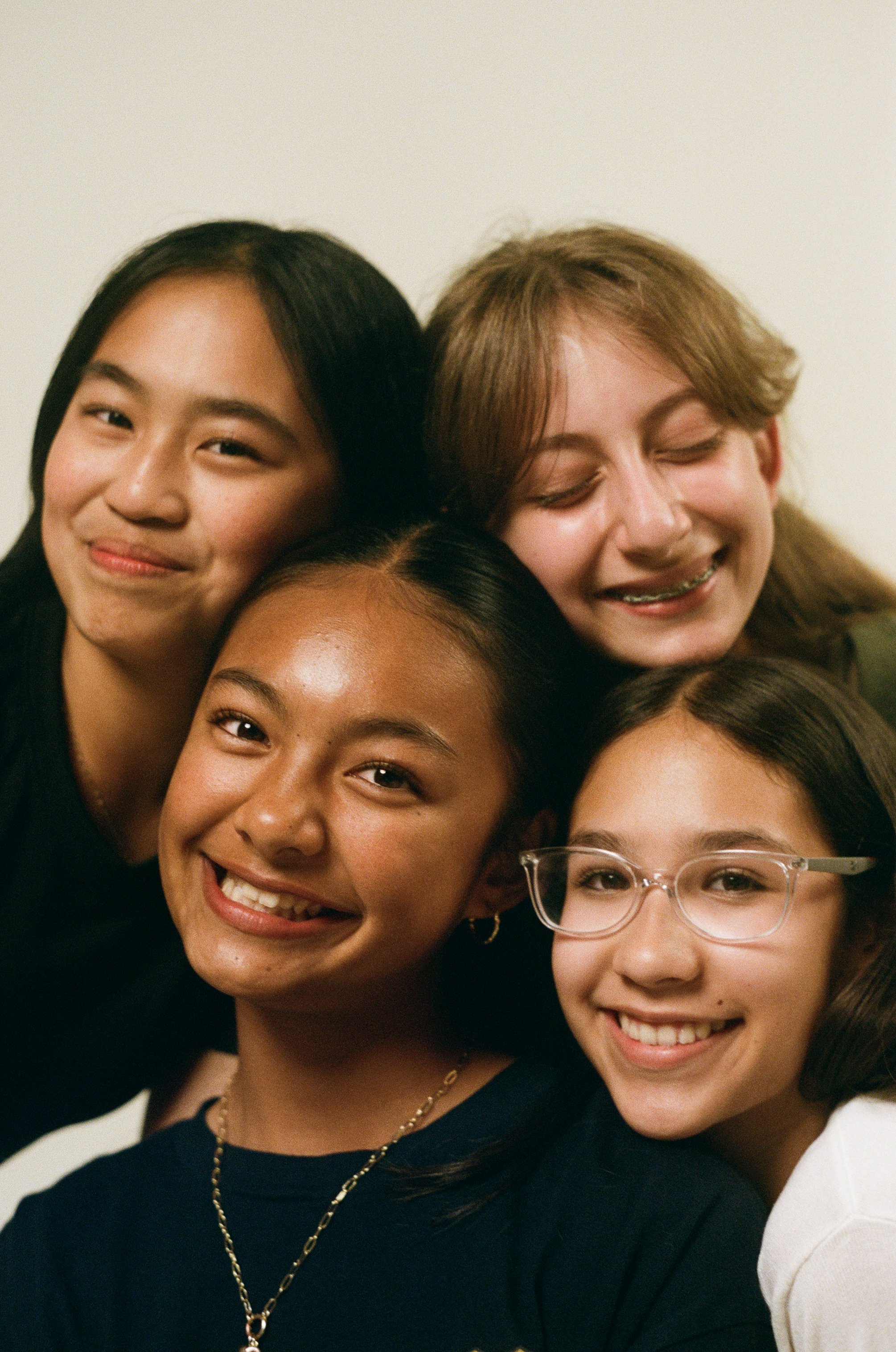 Close-up of smiling young women of diverse ethnicities and appearances, posing together in a group photo.
