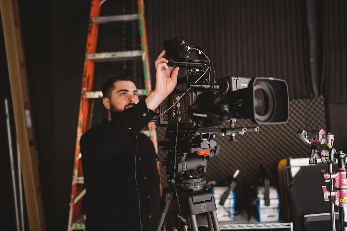 Director operating a cinema camera during a commercial production in studio