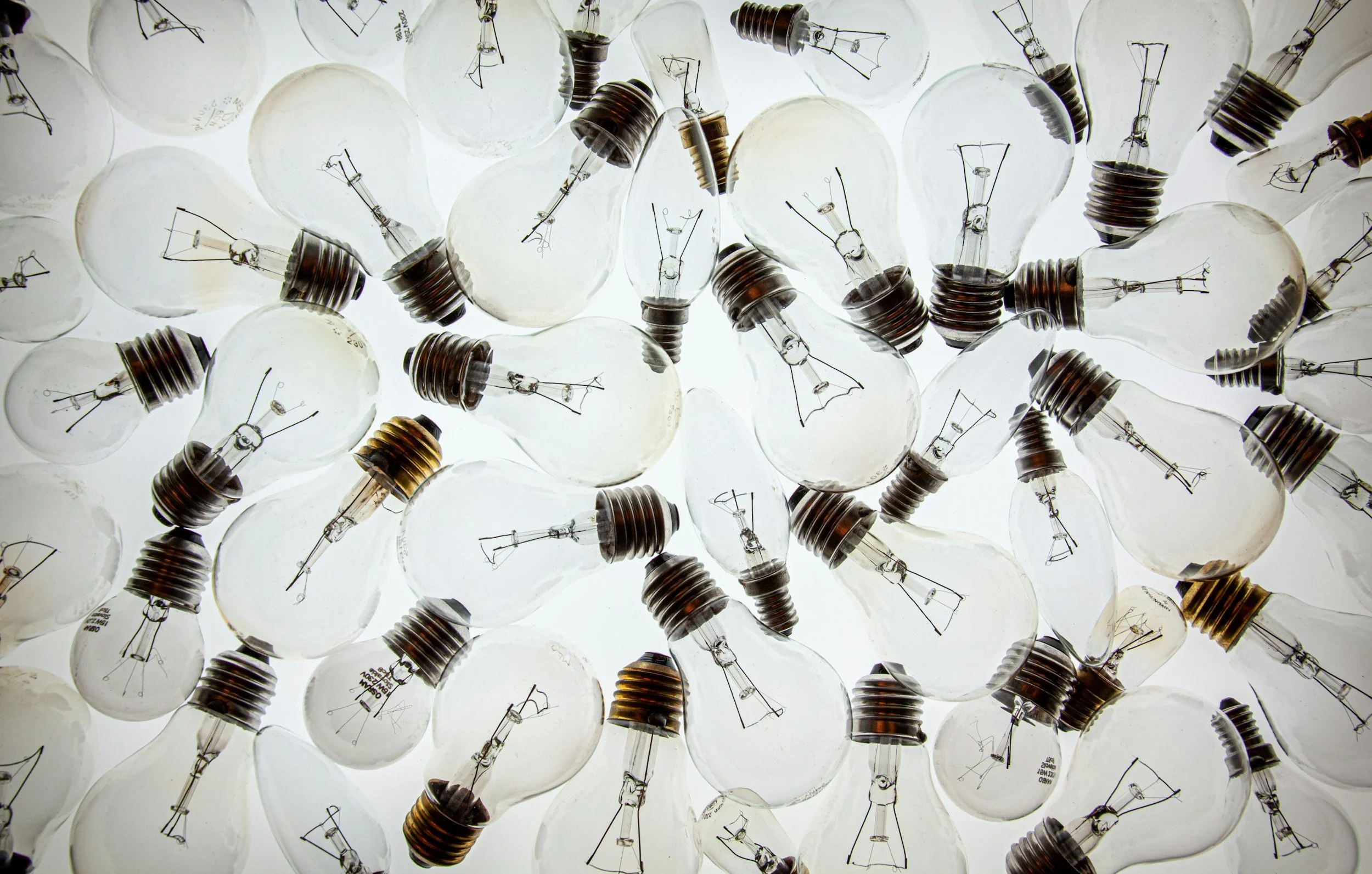 Multiple incandescent light bulbs facing upwards, closely packed together, with visible filaments and metal bases.