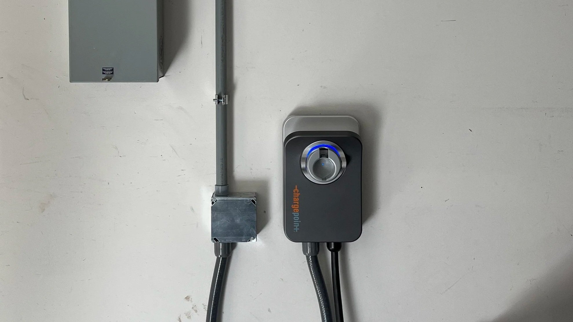 Electrical conduit, switch box, and a gray multi-function circuit device with a circular dial and a visual ring, mounted on a white wall.