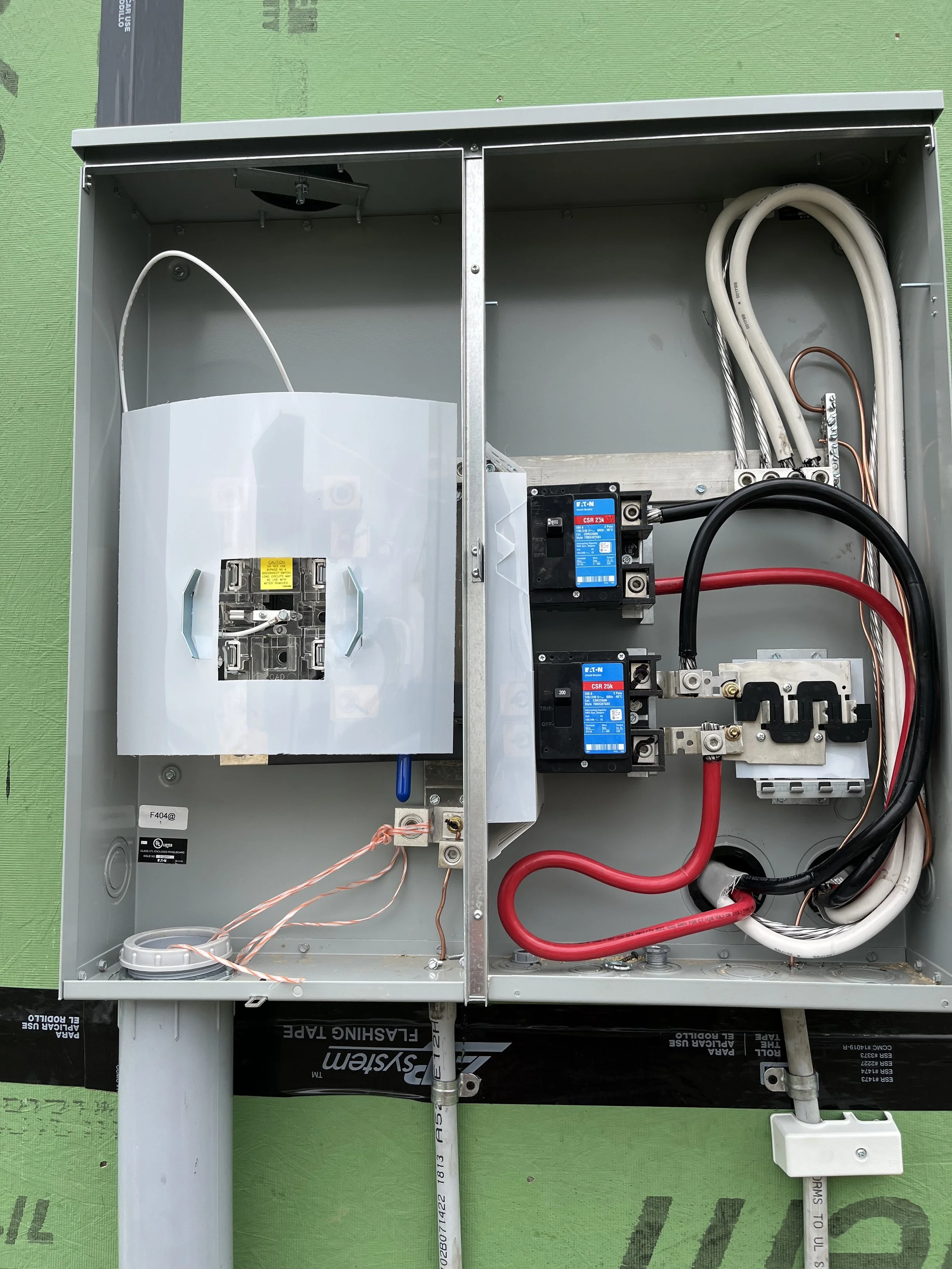 Electrical panel with various wires, circuit breakers, and internal components mounted inside a metal box.