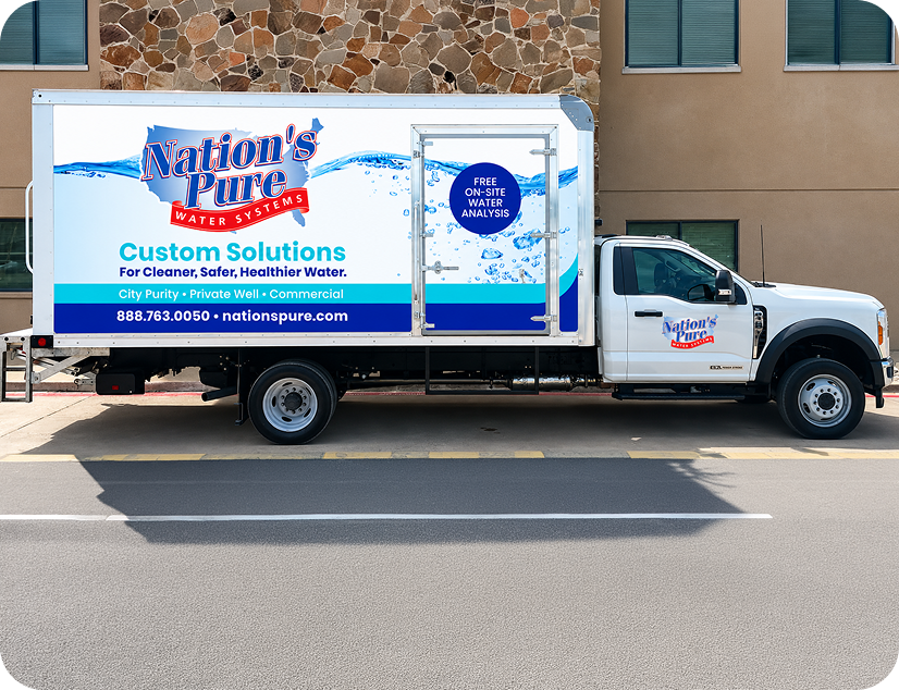 A water delivery truck with branding for Nation's Pure Water Systems parked on the street in front of a building.