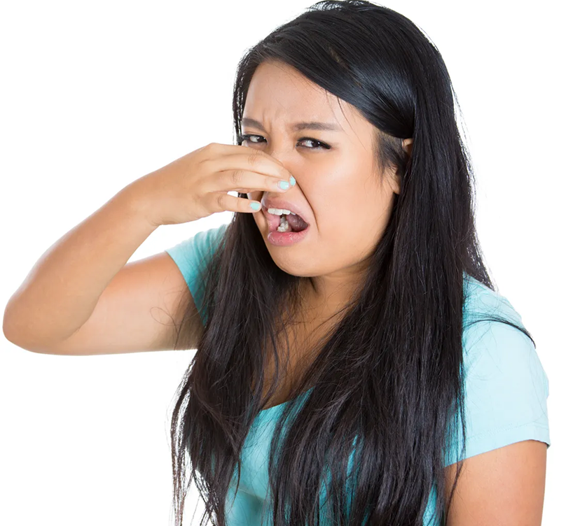Young woman in a turquoise shirt pinching her nose, making a disgusted facial expression.