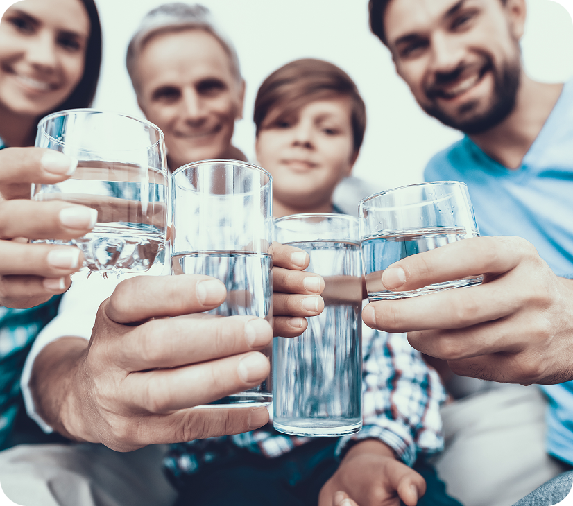 Four people smiling and holding glasses of water in a toast.