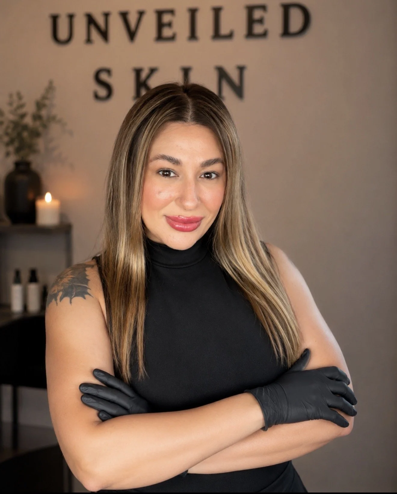 Professional waxing specialist at Unveiled Skin wearing black gloves inside a warm, modern body waxing studio.