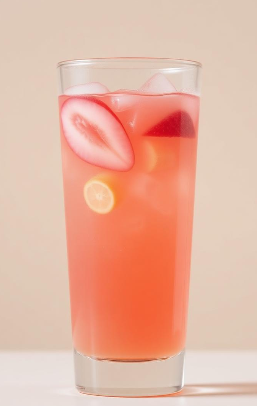 A tall glass of pink-colored beverage with ice cubes, a sliced strawberry, and a lemon slice inside.