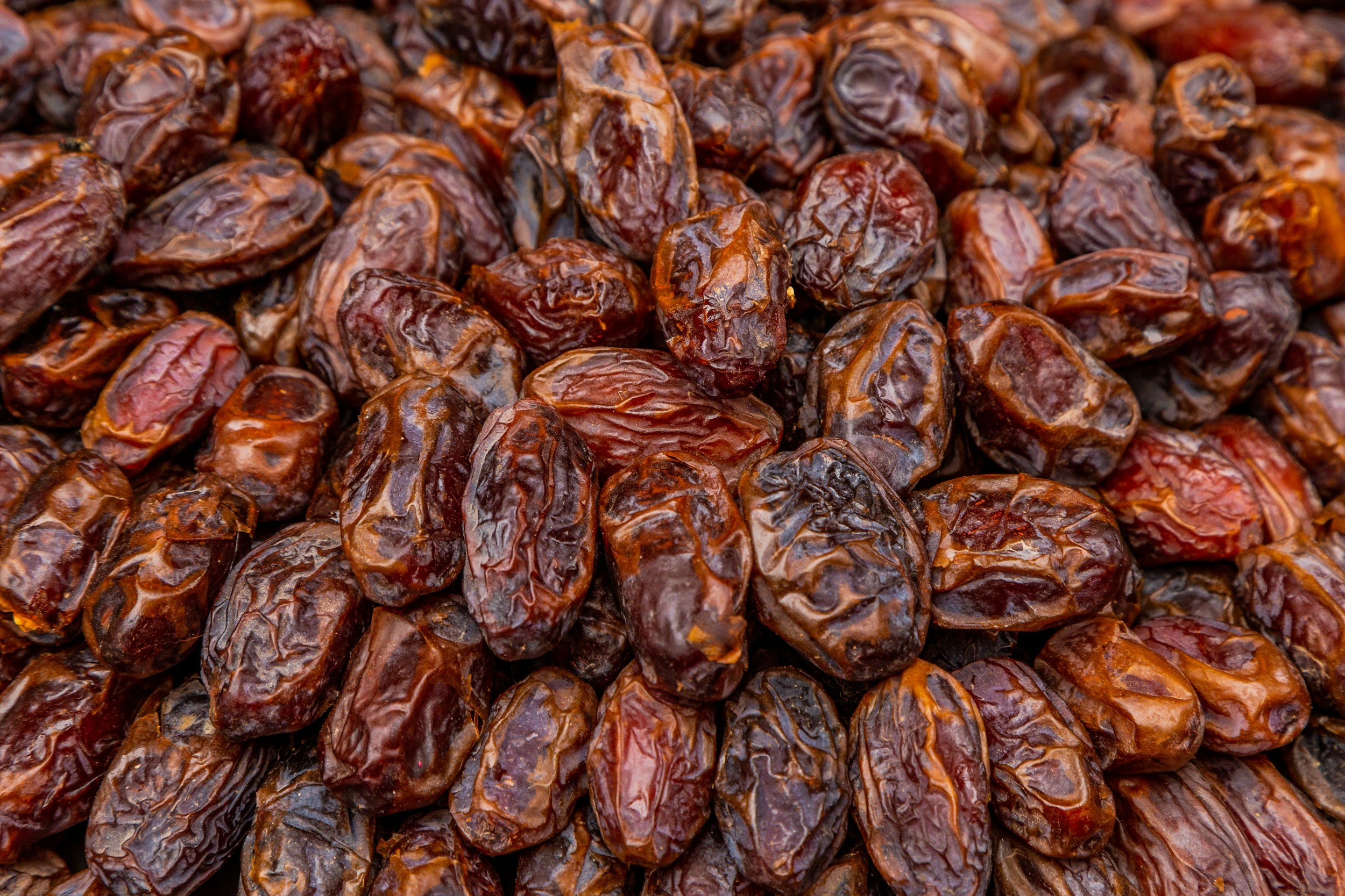 Close-up of numerous dried Medjool dates, showing their wrinkled brown skins.