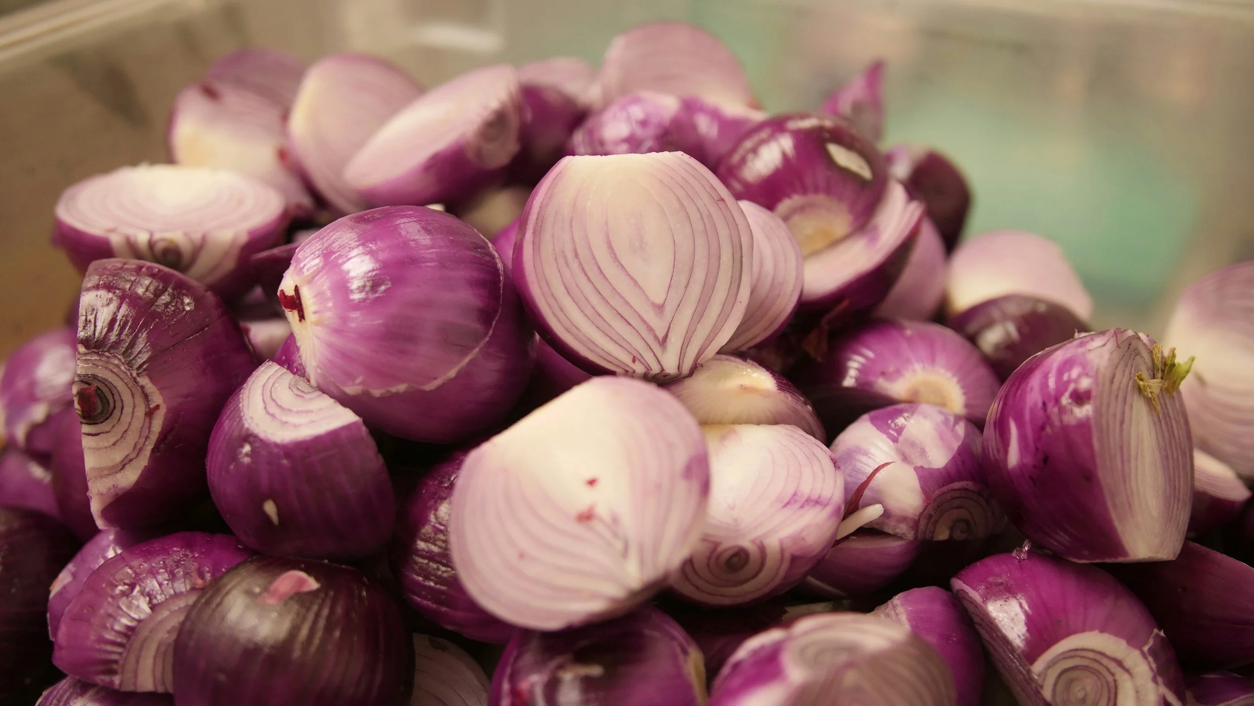 A pile of purple and white shallots with layered skin and visible inner rings.