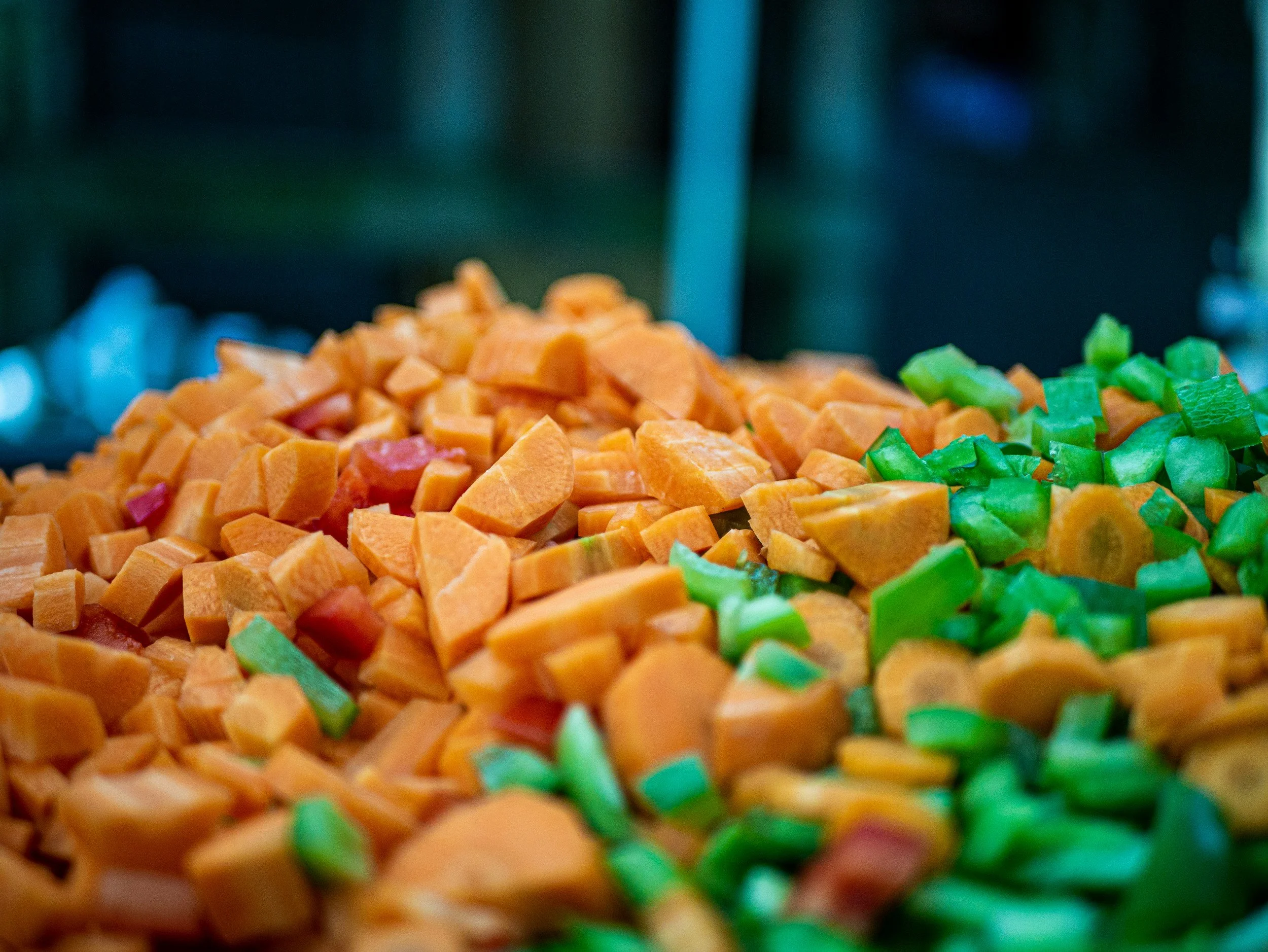 Close-up of diced sweet potatoes and chopped green bell peppers in a cooking or serving dish.