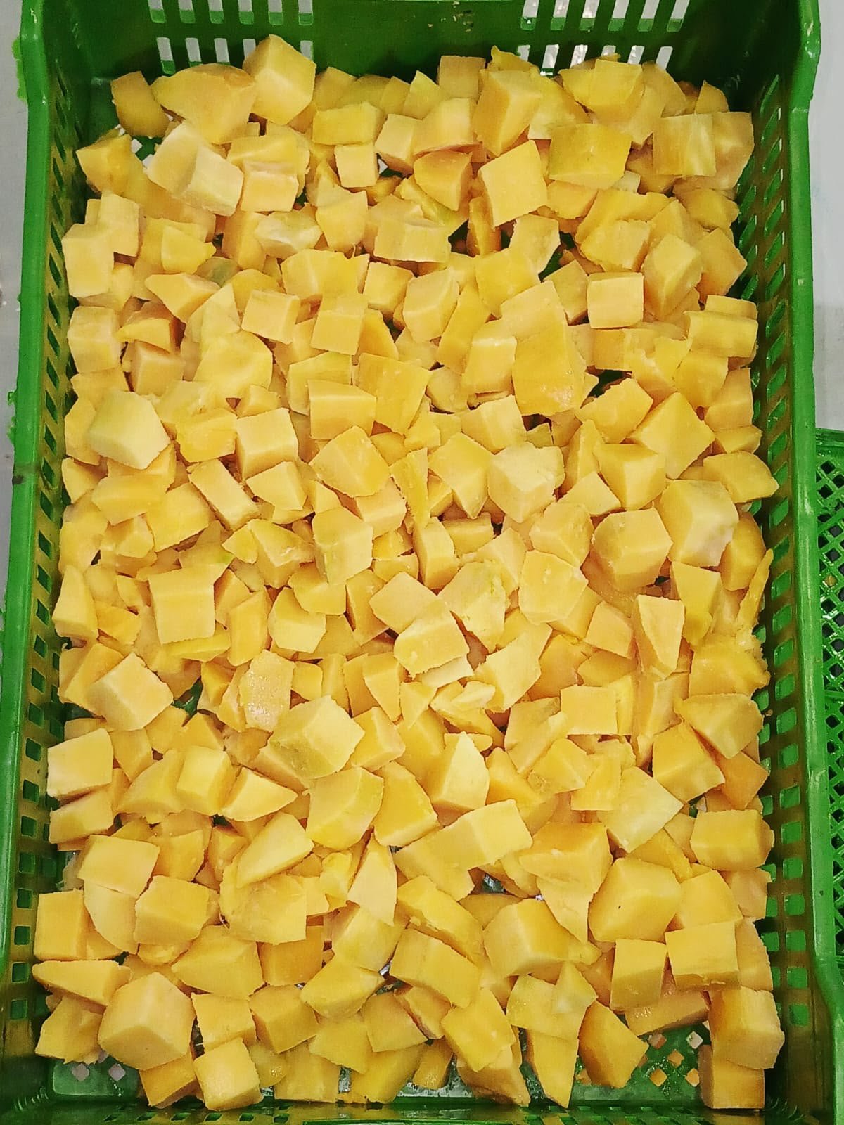 Yellow cubed fruit, likely cheese, in a green plastic basket.