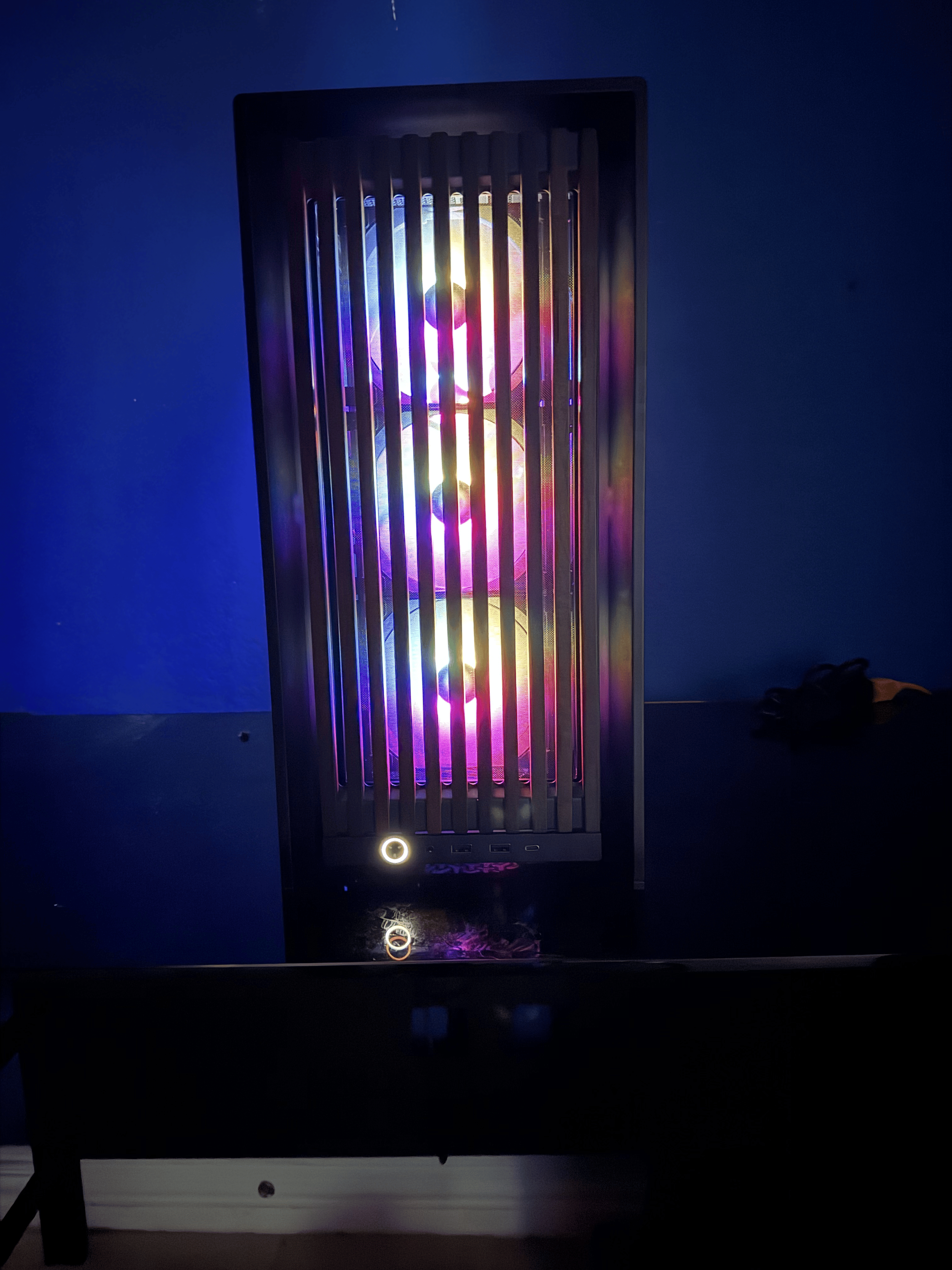 Computer tower with RGB lighting on and a dark background.