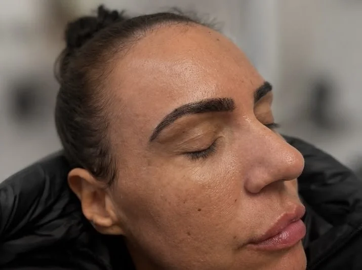 Close-up of a woman with her eyes closed, receiving a facial treatment or skincare procedure.